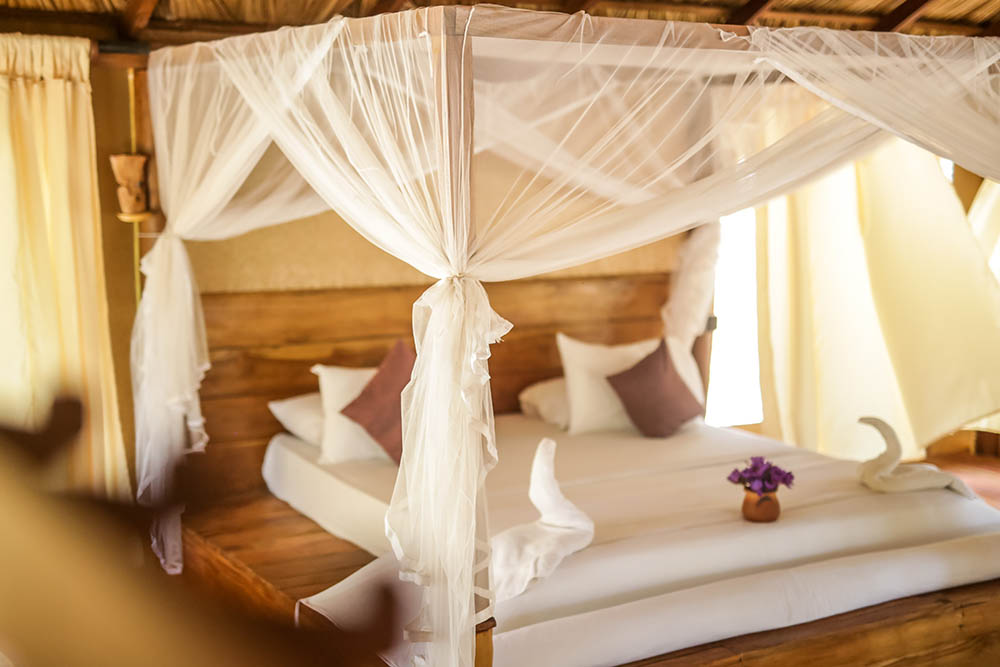 Made-up four-poster bed with swan towel art