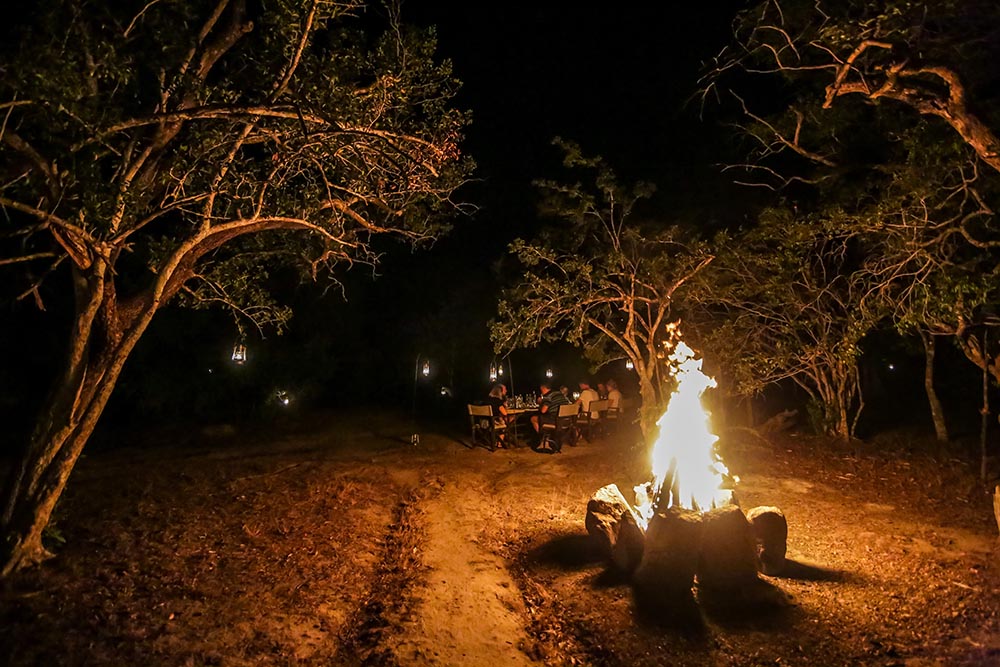 Guests gathered around a bonfire at Yala Tented Camp at night